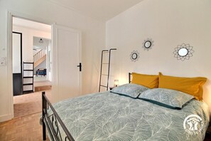 Ein Schlafzimmer mit einem Bett, einer Leiter, einer Tür und einer Treppe, die in einen anderen Raum führt.