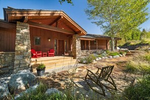 Ein modernes Haus mit Natursteinfassade, einer überdachten Veranda und Sitzgelegenheiten im Freien.