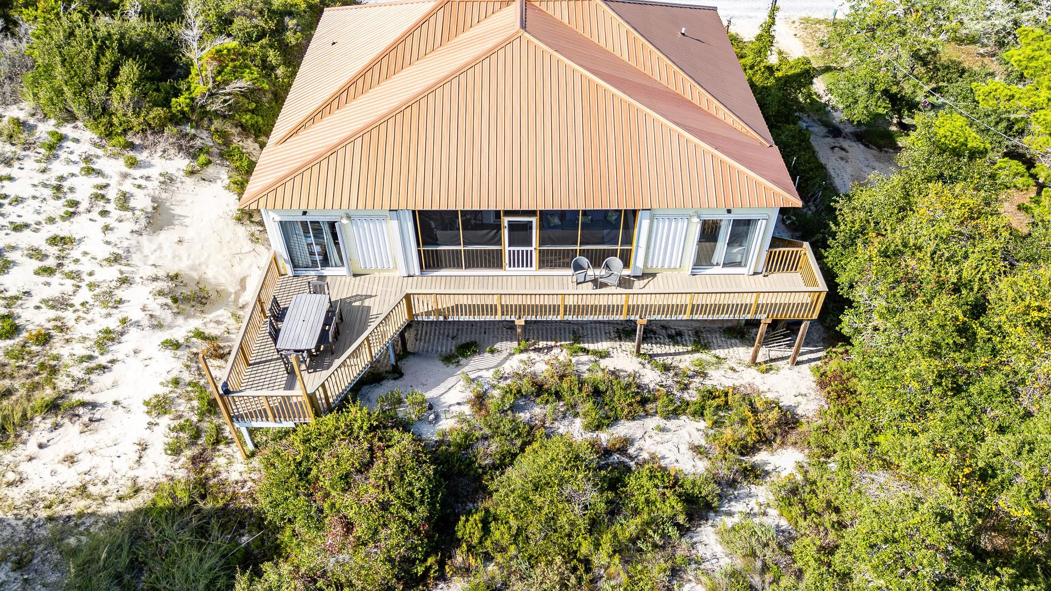 Une propriété située en bord de mer, dotée d’une grande terrasse, de nombreuses fenêtres et d’un toit bien visible.