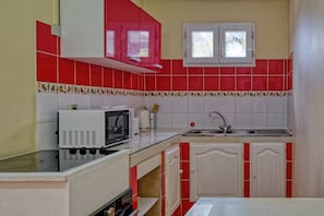 A kitchen with red and white tiles, a microwave, a sink, and cabinets. - Colombe soleil - Climatisation -Terrasse (Rivière-Salée)