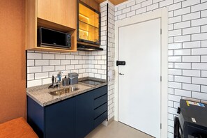 A modern kitchen with a built-in microwave, a stove, and a sink. - Stay Home Itaim - Piscina - Academia (São Paulo)