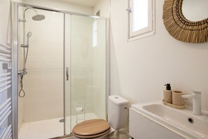 Ein Badezimmer mit Duschkabine aus Glas, Toilette, Waschbecken und Handtuchhalter.