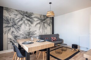 Ein moderner Essbereich mit Holztisch, schwarzen Stühlen und einer grauen Couch.