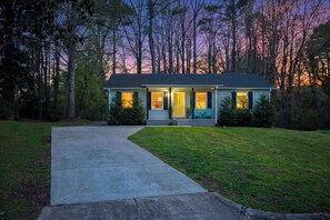 A two-story house with a front porch, a driveway, and a well-maintained lawn. - 13 Guests & Fire Pit, Double Living, 2026 Refresh (Raleigh)