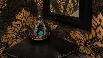 A black-framed mirror with a gold damask pattern on a wall.