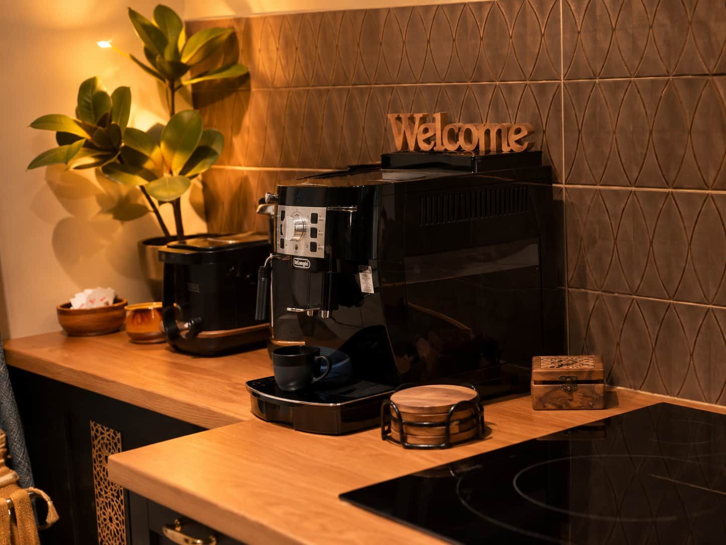 Een koffieapparaat op een houten aanrecht met een 'Welcome'-bord erboven.