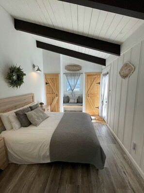Een slaapkamer met een bed, een hoofdbord, een wandlamp, een decoratieve krans en een bord.