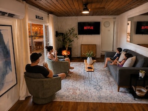 A cozy living room with a fireplace, a television, and a seating area. - Cozy Lakefront Cottage with Fireplace | ATV & Snowmobile Getaway near Bancroft | Sleeps 6 (Faraday)