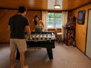 Une pièce avec une table de baby-foot, un jeu de fléchettes et une fenêtre avec des rideaux.