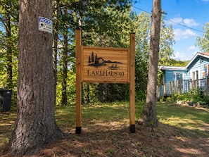 Un letrero de madera con una ilustración de una cabaña y el texto 'LAKEHAUS 40 ON BENTLEY LAKE'.