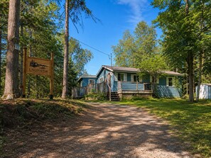 Un chalet rustique appelé «Lakehaus 40», doté d’une véranda et d’un petit abri de jardin, entouré d’arbres et bordé d’un chemin de gravier.