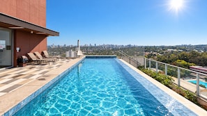 A rooftop swimming pool with a city view, lounge chairs, and a clear sky. - Be Urban Metro Brooklin (São Paulo)