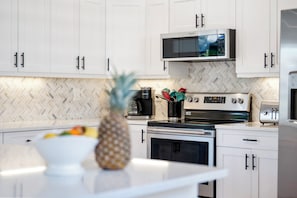 A modern kitchen with white cabinets, a microwave, a coffee maker, and a toaster. - The Triple Naples Collection - 3 Homes • Pools & Spas • King Beds! (Naples)