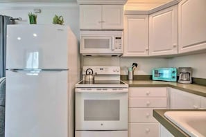 A compact kitchen with a refrigerator, microwave, stove, and a coffee maker. - PB Chic Boho Studio w/ Parking (San Diego)