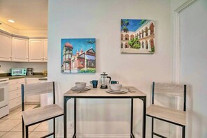 A dining area with a table set for two, two chairs, and a coffee pot on the table. - PB Chic Boho Studio w/ Parking (San Diego)