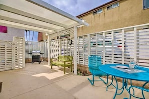 A covered patio area with a grill, a bench, and a table with chairs. - PB Chic Boho Studio w/ Parking (San Diego)