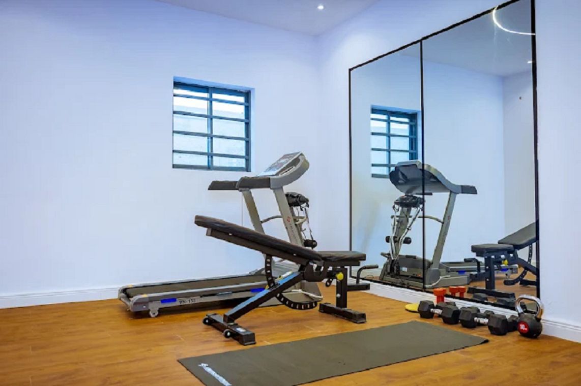 Un gimnasio con cinta de correr, banco de pesas y pesas sueltas.