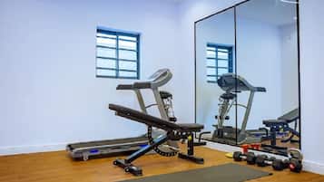 Un gimnasio con equipo de ejercicio, cinta de correr y pesas.