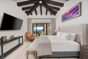 A hotel room with a large bed, a flat-screen TV, a desk with a computer, a chair, and a view of the outdoors. - Beautiful House at Coronado Quivira Golf Course (Cabo San Lucas)