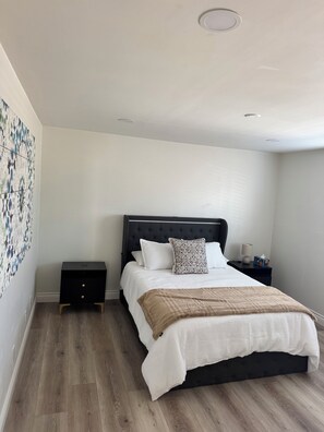 A bedroom with a bed, bedside tables, and a wall with a patterned artwork. - Surfcity Getaway 5min walk to beach and Main St (Huntington Beach)