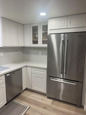 A modern kitchen with white cabinetry, a stainless steel refrigerator, and a built-in oven. - Surfcity Getaway 5min walk to beach and Main St (Huntington Beach)