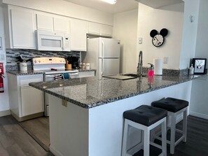 A modern kitchen with white cabinetry, a granite countertop, a built-in oven, and a refrigerator. - Family-Friendly 3BR/2BA Condo Minutes from Disney with Pool & Gym (Kissimmee)