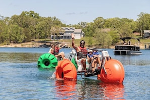 A group of people on a watercraft with pontoons, surrounded by calm water and trees. - Still Waters Resort 1BR Condo – Pools, Lake & Marina (Branson)