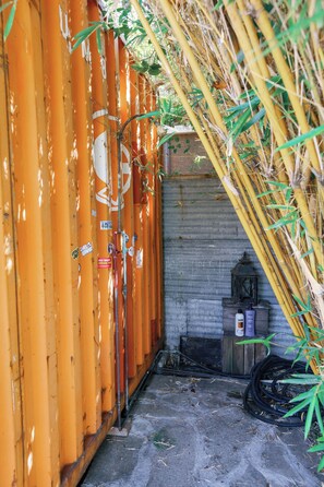 An outdoor area with a corrugated metal wall, a wooden structure, and a metal container. - Venice Urban Farm 3BR Sauna RV & Chickens! (Los Angeles)