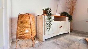 A wicker chair, a white cabinet with plants, and a wooden floor. - Bohemian-style flat with swimming pools, near the beach (Vera)