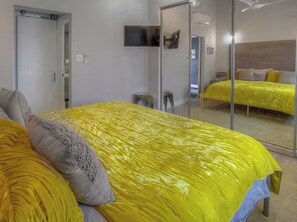 Ein Zimmer mit einem Bett, einem Spiegel und einem Fernseher.