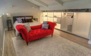 Ein Schlafzimmer mit einem Bett, einem roten Sofa, einem begehbaren Kleiderschrank und Holzboden.