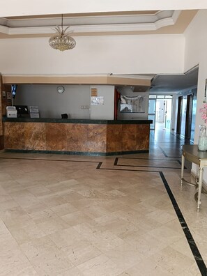 A reception area with a marble counter, a clock, and a chandelier. - Apartment, Ocean View (Cartagena de Indias)
