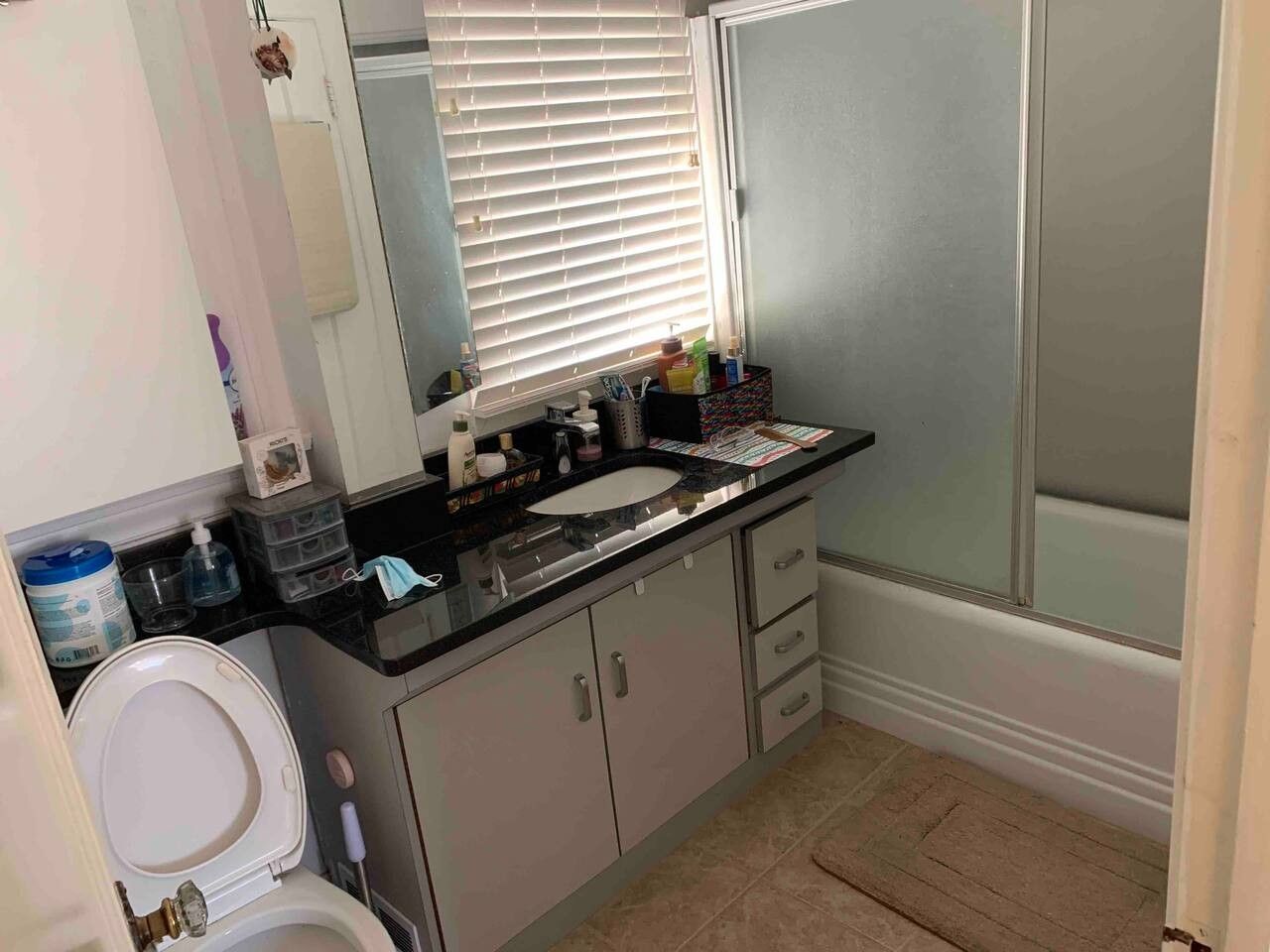 A bathroom with a toilet, sink, mirror, and shower area.