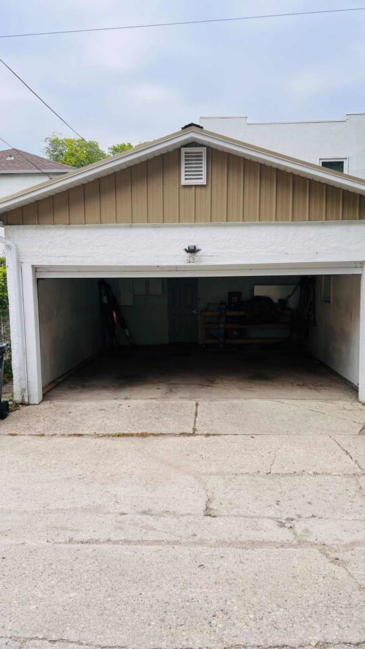 A garage with a sloped roof, a vent on the wall, and a concrete floor.