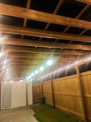 Una struttura in legno all'aperto con una serie di luci lungo il soffitto.