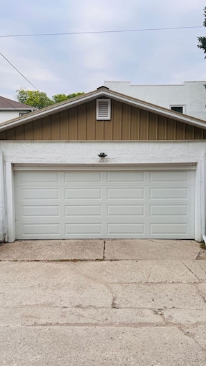 Eine Garage mit weißer Tür, braunem Dach und Betonauffahrt.