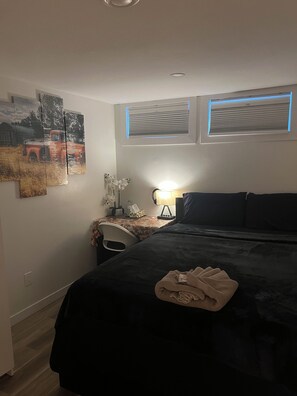 A hotel room with a bed, a nightstand, a lamp, and wall art.