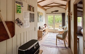A cozy room with a wooden bench, a small table with a lamp, and a view of the outdoors through a glass door. - 2 bedroom awesome home in Glesborg (Glesborg)