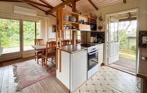 Una cucina compatta con forno a incasso, un tavolo da pranzo con sedie e vista all'esterno tramite una porta vetrata.