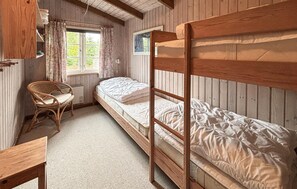 A bunk bed room with a wooden headboard, a wicker chair, and a window with curtains. - 2 bedroom awesome home in Glesborg (Glesborg)