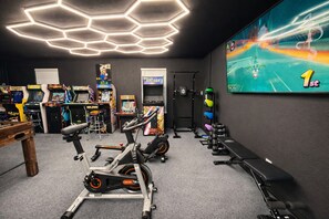 A gym with exercise bikes, a treadmill, and various arcade games. - 8BR Vegas Retreat! Strip Views, Pool, Spa, Sauna, Gym, Gameroom +2 Casitas ★★★★★ (Las Vegas)