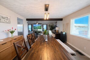 A spacious dining area with a long wooden table, chairs, and a central vase. - 8BR Vegas Retreat! Strip Views, Pool, Spa, Sauna, Gym, Gameroom +2 Casitas ★★★★★ (Las Vegas)