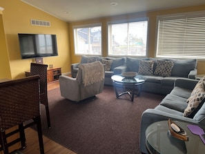 Ein Wohnzimmer mit Sofa, Sessel, Couchtisch und Fernseher.