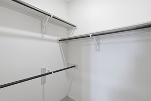 Una esquina de una habitación con paredes blancas y barras de toallas de metal.