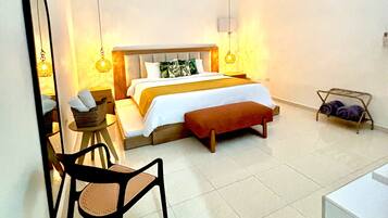 A bedroom with a bed, a chair, a bedside table, a hanging light, and a ceiling fan.