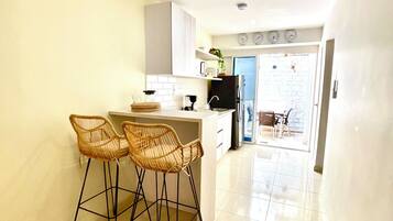 A kitchen with a bar area, white cabinets, and a tiled floor.