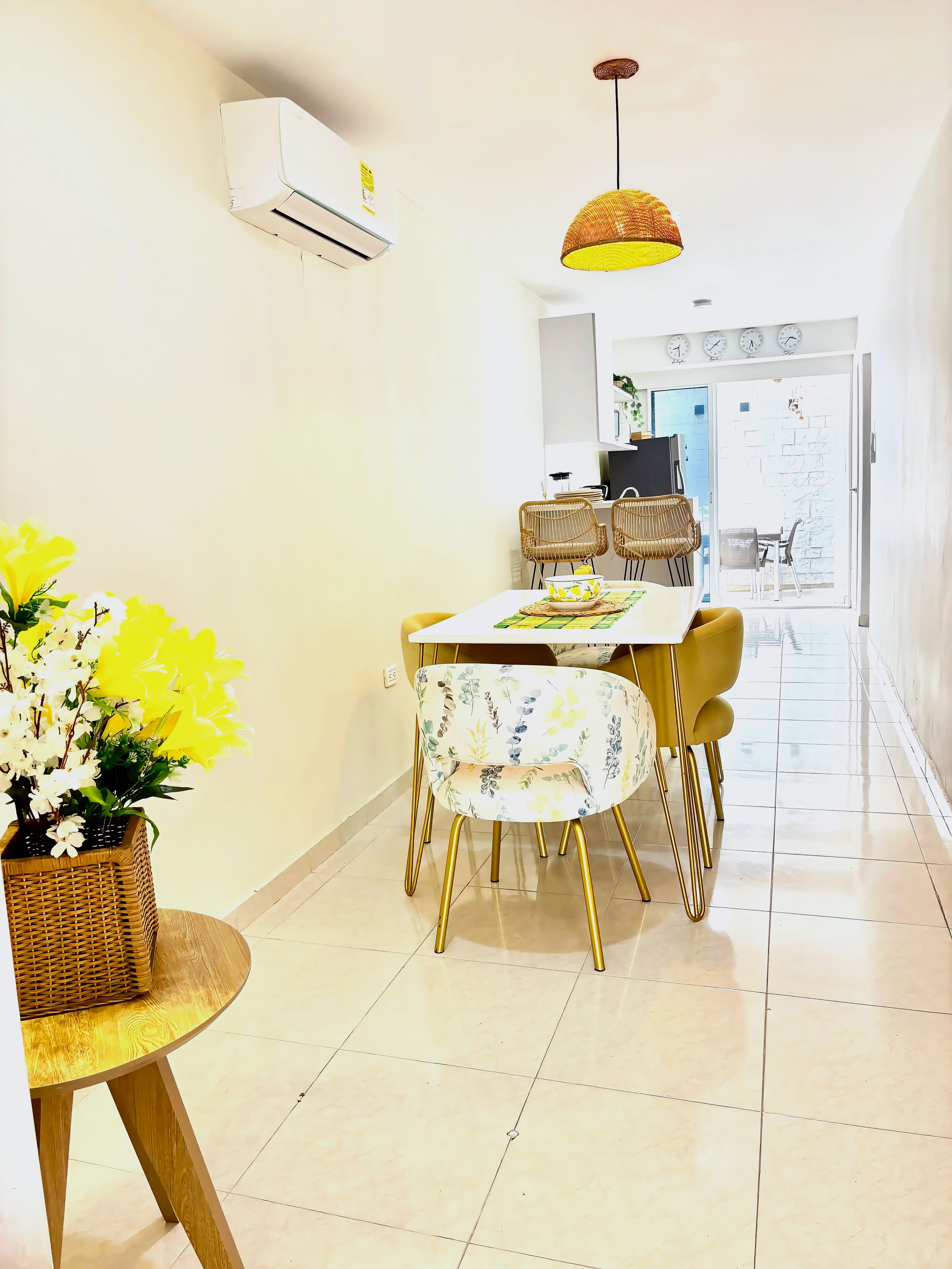 A dining area with a table, chairs, a hanging light fixture, and a potted plant.