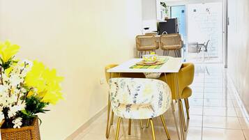 A dining area with a table, chairs, a hanging light fixture, and a potted plant.
