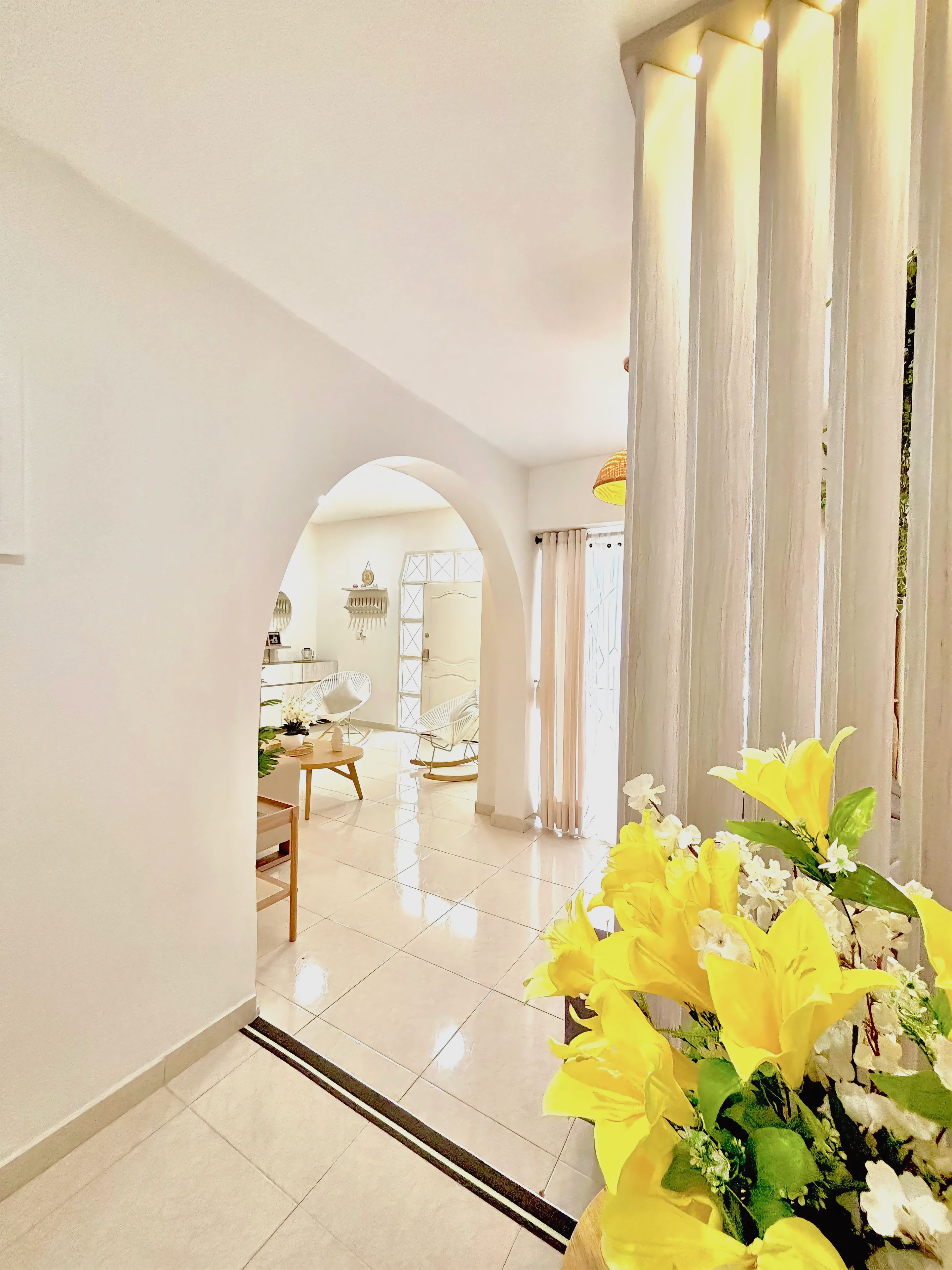 A hallway with a tiled floor leading to a dining area with chairs and a table.
