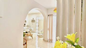 A hallway with a tiled floor leading to a dining area with chairs and a table.